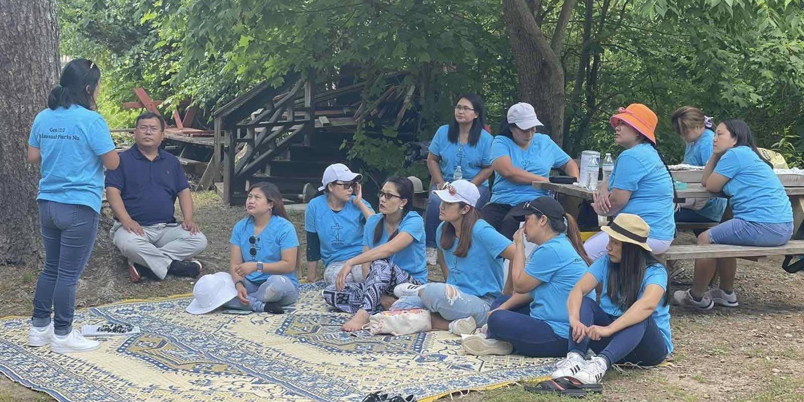 people in blue shirts attending out door event on blanket for Home of Helping Hand to donate