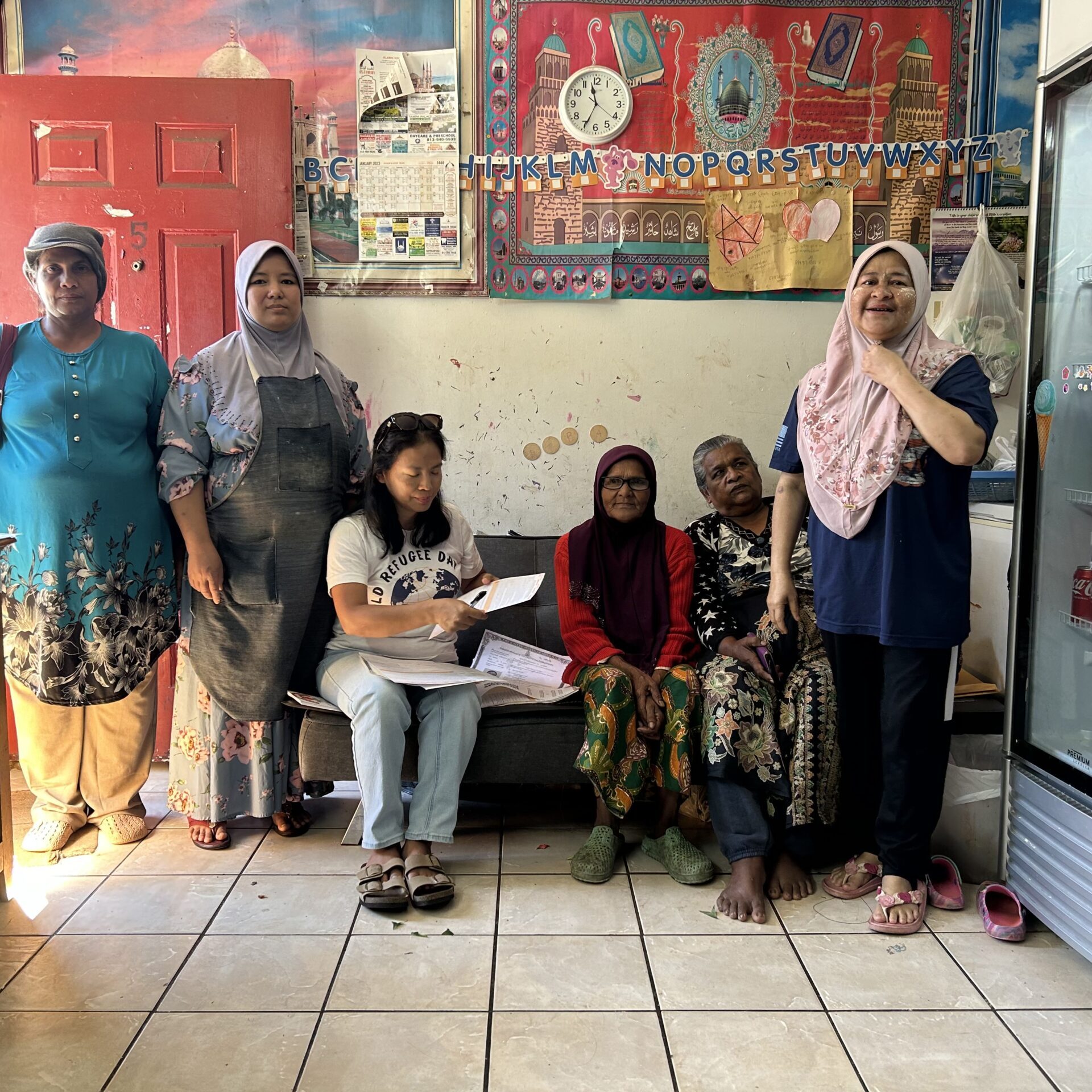 women standing in house with posters on wall and soda refrigerator on the side